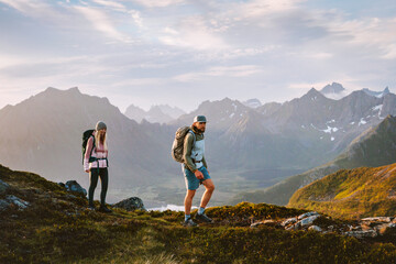 Couple hiking in Norway friends man and woman travel active extreme vacations healthy lifestyle trip, family hikers climbing mountains in Lofoten islands adventure trip tourists with backpacks outdoor