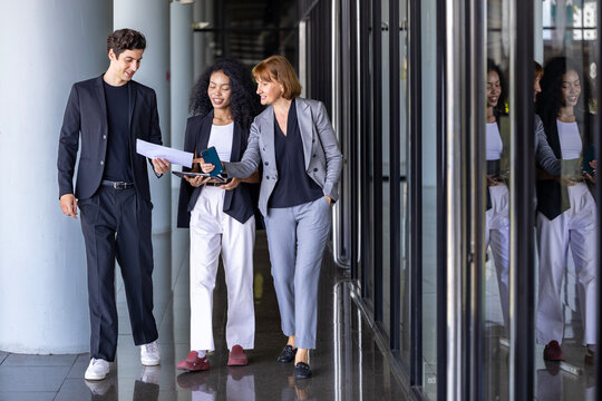 Team of diversity business people are discussing over the new strategic strategy projects on investment real estate while walking around the office building for new project and planning - Powered by Adobe
