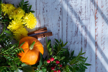 Autumn bright colored background for text, a composition of pumpkins, yellow flowers, and green...
