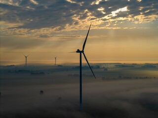 Aerial view of a windmill farm on a foggy autumn day, with beautiful light and colours, a unique...