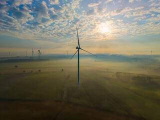 Aerial view of a windmill farm on a foggy autumn day, with beautiful light and colours, a unique...