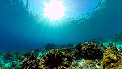 Naklejka premium Sunlight piercing through clear blue ocean water illuminating a healthy coral reef.