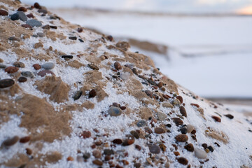 Close-up view of snow-covered rocks and sand, showcasing textures and colors in a winter landscape, highlighting the beauty of nature in cold environments with copy space
