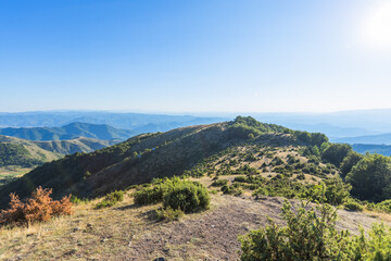 Stunning mountain ridge landscape with layered hills extending to horizon under clear blue sky