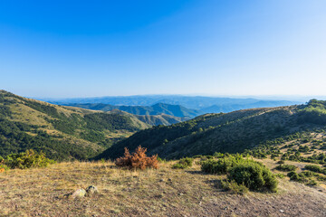 Naklejka premium Stunning mountain ridge landscape with layered hills extending to horizon under clear blue sky