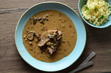 Top view of a traditional Czech dish — beef with mushrooms — served on a blue plate. A...