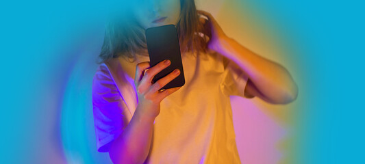 Woman texting SMS message on mobile phone. Woman holding smartphone and reading message on a neon glowing background