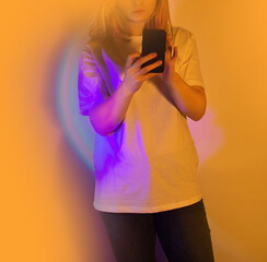Cheerful young woman writes a text message with her mobile. Woman using mobile phone to give...