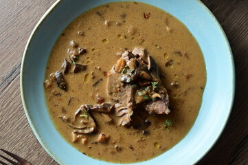 Top view of a traditional Czech dish — beef with mushrooms — served on a blue plate. A...