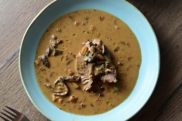 Top view of a traditional Czech dish — beef with mushrooms — served on a blue plate. A...
