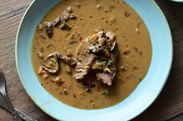 Top view of a traditional Czech dish — beef with mushrooms — served on a blue plate. A...