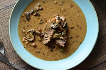Top view of a traditional Czech dish — beef with mushrooms — served on a blue plate. A...