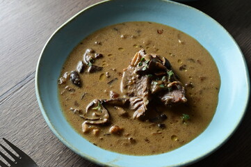 Top view of a traditional Czech dish — beef with mushrooms — served on a blue plate. A...