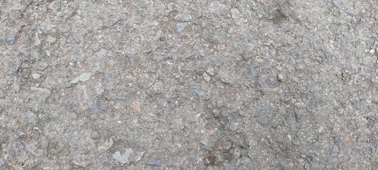 Close-up of a rough, gray surface with small stones and debris, creating a textured and uneven ground.