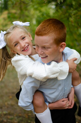 Fototapeta premium A little girl sits on the boy back and hugs him with her arms.