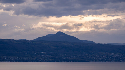 Pyramid-shaped mountain and Alps at cloudy sunset over Lake Geneva