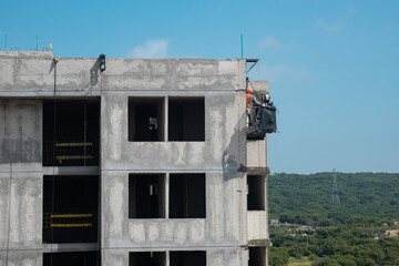 Construction Worker on Suspended Platform Repairing Building Facade