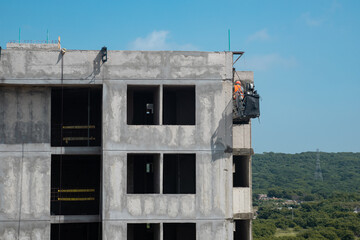 Construction Worker on Suspended Platform Repairing Building Facade