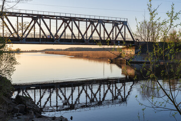 Old railway bridge in Jugla, Riga over the river at sunset in spring between two lakes - Ķīšezers and Juglas lake