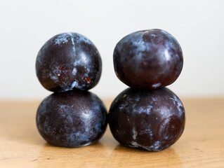 Fresh Plums Stacked on a Wooden Surface in Natural Light