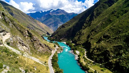 High-angle view of a turquoise river winding through a valley surrounded by lush green mountains and a winding road
