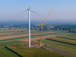 Installing a new wind turbine in the field using a crane to provide clean, carbon-neutral...