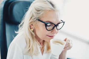 Charming businesswoman sipping coffee and enjoying a moment of relaxation in a modern urban...