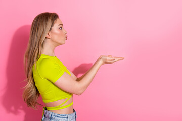 Charming young woman making a playful hand gesture against a vibrant pink background wearing casual...