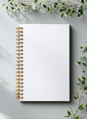 Blank spiral-bound notebook, surrounded by greenery