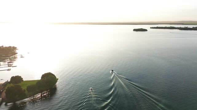 Imagens de uma lancha no rio ao por do sol feitas por drone