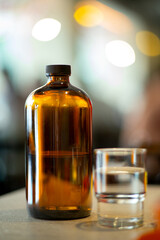 Amber glass bottle with cap placed on table in cafe, modern minimalist design, lifestyle concept, blurred bokeh background scene