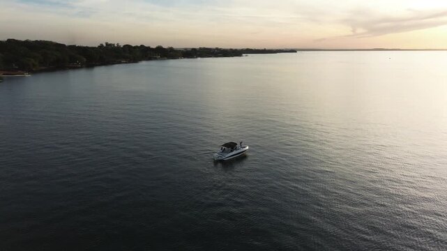 Imagens de uma lancha no rio ao por do sol feitas por drone