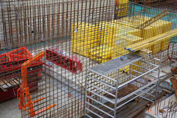 Industrial construction background with metal rebar, scaffolding and colorful equipment at building...