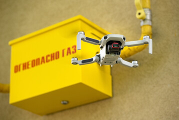 Drone in the air inspecting gas box and pipe, and text Flammable Gas on wall dangerous closeup yellow wall