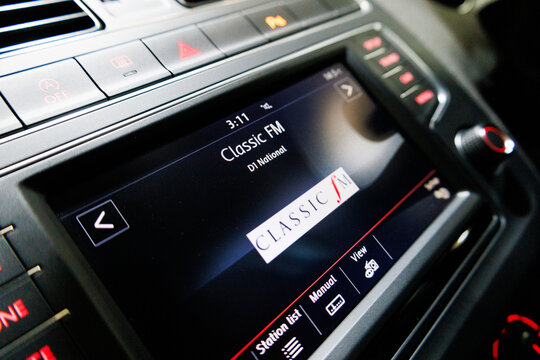 A close-up shot of a car's infotainment system displaying Classic FM on a digital DAB radio interface