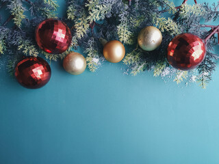 green background with gold and red Christmas balls and pine branch and space for text
