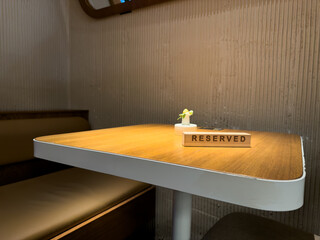 Reserved sign on restaurant table in cozy booth, emphasizing importance of early reservation in...