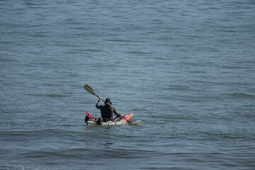 Saint-Aubin-Sur-Mer, France - 08 11 2025: A man in diving suit rows a canoe on the sea