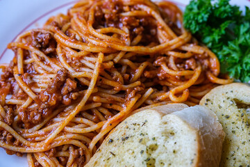 Italian Style Spaghetti Bolognese With Garlic Bread And Parsley Garnish