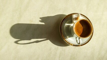 Turkish coffee in a decorative cup with a piece of sweet, top view with shadow