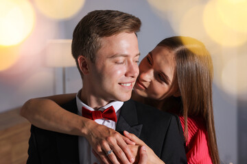 Making marriage proposal. Woman with engagement ring and her smiling fiance hugging at home. Bokeh effect