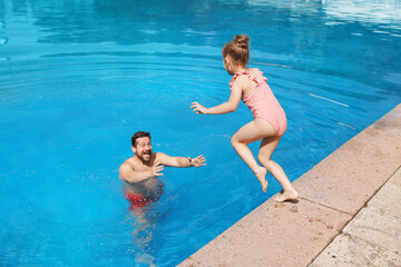 Father and his daughter having fun in swimming pool outdoors. Family vacation