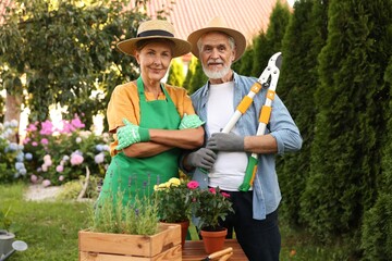 Happy senior couple in gloves and hats in garden