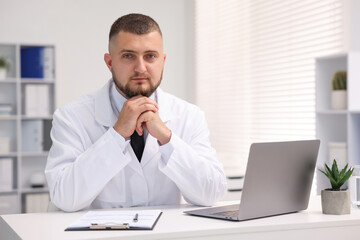 Fototapeta premium Doctor working at table with laptop in clinic. Online medical consultation