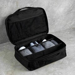 Black travel toiletry bag with mesh compartments, neatly organized personal care items, ideal for travel enthusiasts seeking convenience and functionality in grooming essentials