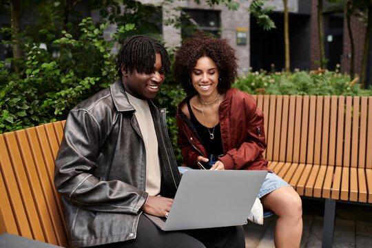 Young couple collaborating on remote work project in vibrant city setting - Powered by Adobe