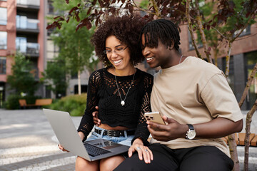 Stylish young couple working remotely together in an urban setting on a sunny day