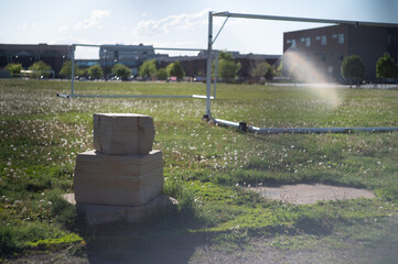 piled stone blocks on a grass field with two abandoned soccer goals