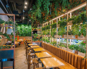 Indoor restaurant filled with hanging plants, shelves of foliage, and natural wooden furniture creating an inviting and organic ambiance.