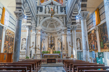 Interior of a grand church featuring white marble columns and statues, with pews leading to a...